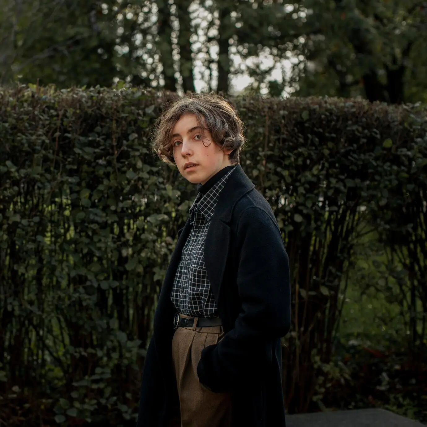 Небинарный человек позирует на открытом воздухе.