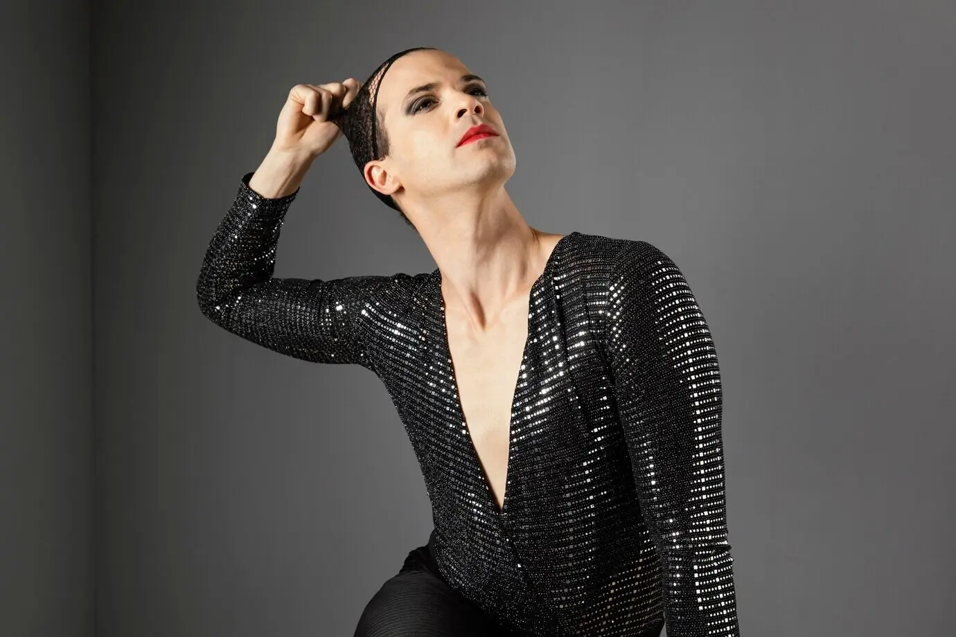 Молодой трансгендерный человек снимает свою сетку для волос.