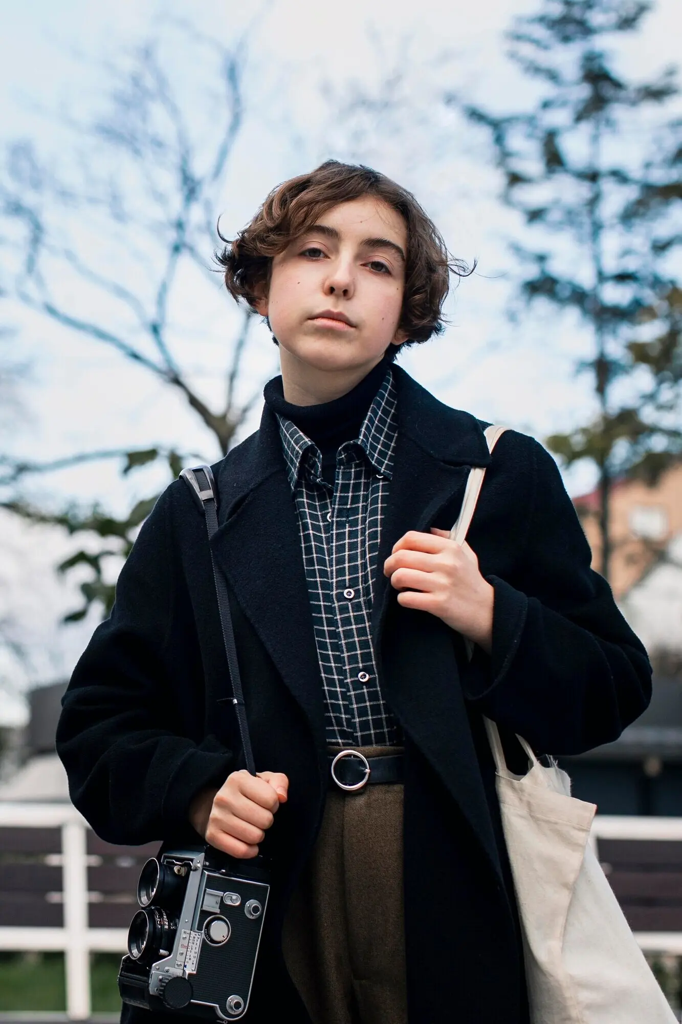 Небинарный человек стоит снаружи, вид спереди.